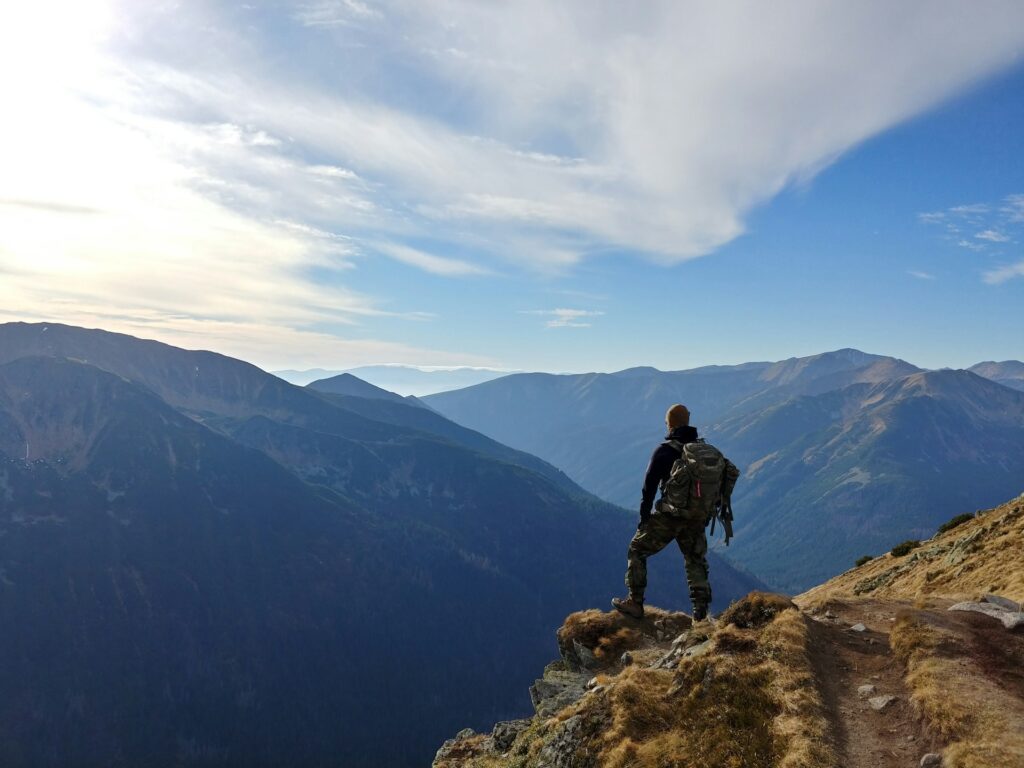 Man on top of mountain under blue sky